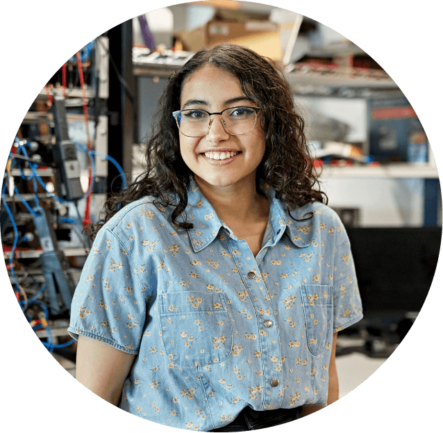 young woman in glasses smiling and standing in front of network equipment